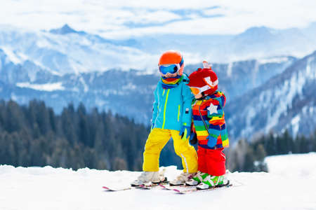 Child skiing in the mountains. Kid in ski school. Winter sport for kids. Family Christmas vacation in the Alps. Children learn downhill skiing. Alpine ski lesson for boy and girl. Outdoor snow fun.の写真素材