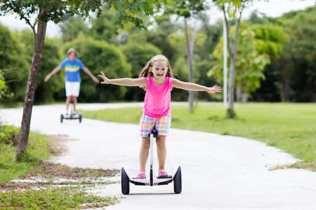 Child on hover board. Kids riding scooter in summer park. Balance board for children. Electric self...