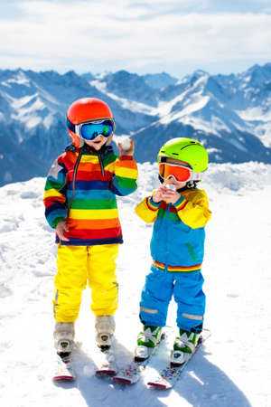 Child skiing in the mountains. Kid in ski school. Winter sport for kids. Family Christmas vacation in the Alps. Children learn downhill skiing. Alpine ski lesson for boy and girl. Outdoor snow fun.の写真素材