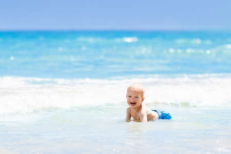 Child on beautiful beach. Little boy running and jumping at sea shore. Ocean vacation with kid. Children play on summer beach. Water fun. Kids run and swim. Family holiday on tropical island.の写真素材