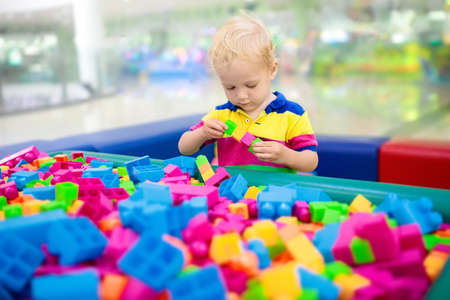 Child playing with colorful construction toy blocks. Educational toys for young kids. Kindergarten or preschool play room. Toddler kid at day care playground. Boy building house with block at daycareの写真素材