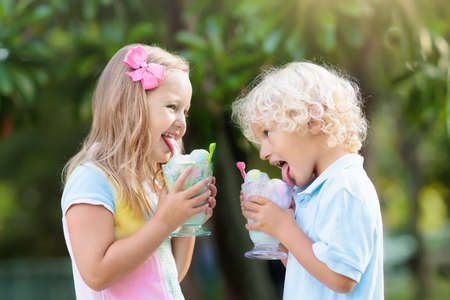 Kids eating ice cream on hot summer day on tropical vacation. Children eat frozen yoghurt. Boy and girl with healthy fruit and dairy snack. Family summer holiday fun. Banana and strawberry sorbet.の写真素材