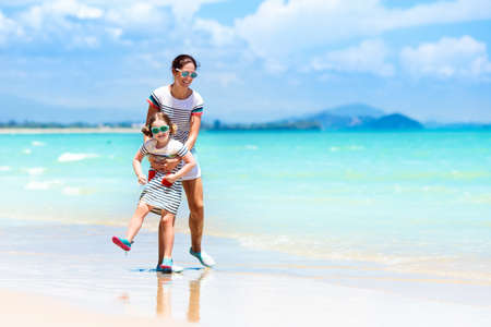 Mother and child playing at tropical beach. Family sea summer vacation. Mom and kid girl play and build sand castle. Ocean and water fun for parent and kids. Fit and healthy family at exotic beach.の写真素材