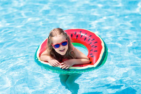Child with watermelon. Little girl learning to swim in outdoor pool of tropical resort. Kid eye...