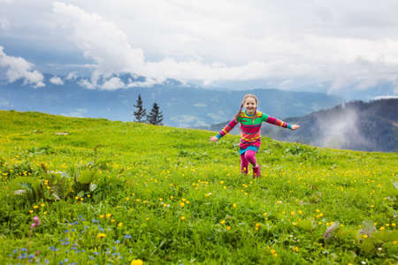 Little girl on hike trail in blooming alpine meadow. Outdoor fun and healthy activity.の写真素材