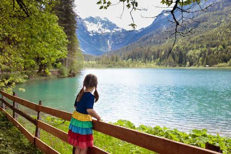 Child hiking in the Alps mountains looking at beautiful lake.の写真素材
