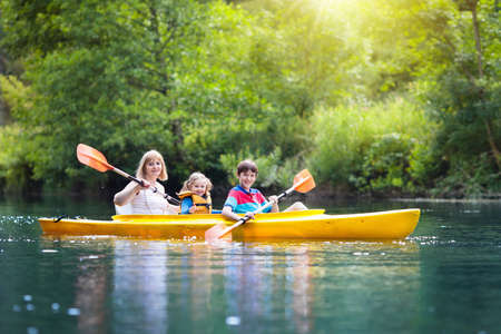 Child with paddle on kayak. Summer camp for kids. Kayaking and canoeing with family. Children on canoe. Little boy on kayak ride. Wild nature and water fun on summer vacation. Camping and fishing.の写真素材