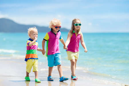 Child playing on tropical beach. Little girl digging sand at sea shore. Family summer vacation. Kids...
