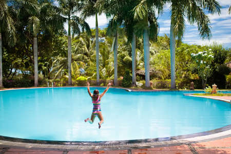 Child with goggles in swimming pool. Little girl learning to swim and dive in outdoor pool of tropical resort. Swimming with kids. Healthy sport activity for children. Sun protection. Water fun.の写真素材