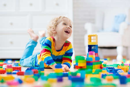 Child playing with colorful toy blocks. Little boy building tower at home or day care. Educational...