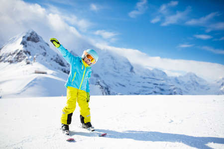 Child skiing in the mountains. Kid in ski school. Winter sport for kids. Family Christmas vacation in the Alps. Children learn downhill skiing. Alpine ski lesson for boy and girl. Outdoor snow fun.の写真素材