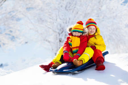 Little girl and boy enjoying sleigh ride. Child sledding. Toddler kid riding a sledge. Children play...