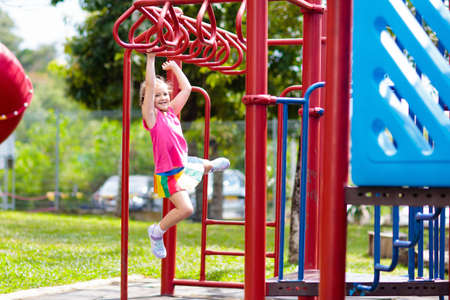 Child on monkey bars. Kid at school playground. Little girl hanging on gym activity center of...