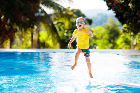 Child playing in swimming pool. Summer vacation with kids. Little boy jumping into water during exotic holiday in tropical island resort. Children swim. Active outdoor sport for preschooler.の写真素材