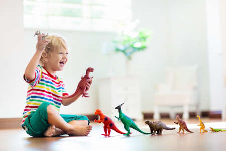 Child playing with colorful toy dinosaurs. Educational toys for kids. Little boy learning fossils and reptiles. Children play with dinosaur toys. Evolution and paleontology game for young kid.の写真素材