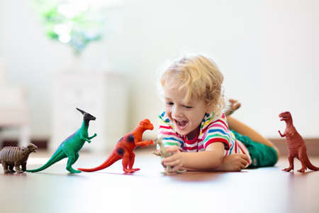 Child playing with colorful toy dinosaurs. Educational toys for kids. Little boy learning fossils and reptiles. Children play with dinosaur toys. Evolution and paleontology game for young kid.の写真素材