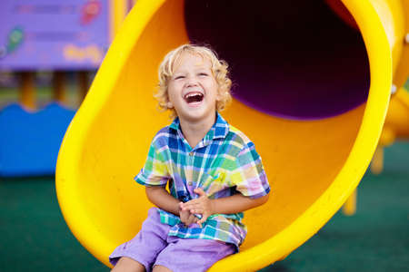 Child playing on outdoor playground. Kids play on school or kindergarten yard. Active kid on...
