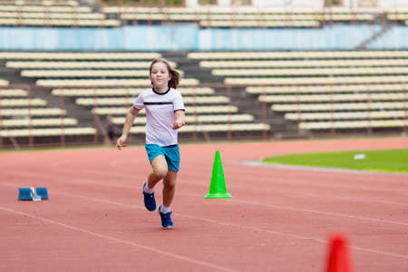Child running in stadium. Kids run on outdoor track. Healthy sport activity for children. Little girl at athletics competition race. Young athlete in training. Runner exercising. Jogging for kid.の写真素材