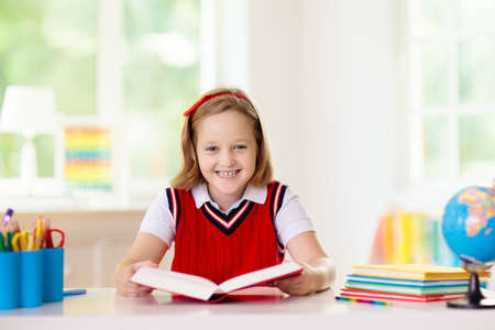 Kids go back to school. Children study and learn for preschool. Little girl of elementary class doing homework. Bedroom with desk, books and globe for young child. Kid learning to read and write.の写真素材
