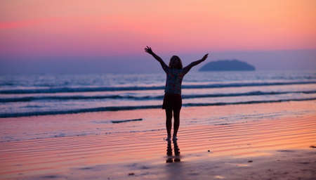 Child playing on ocean beach. Kid jumping in the waves at sunset. Sea vacation for family with kids....