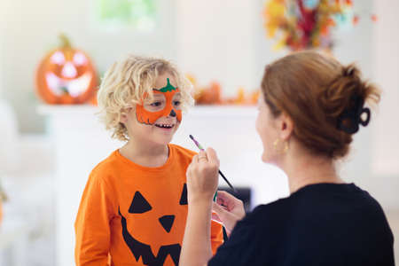 Child and mother in Halloween costume. Kids trick or treat. Face painting for party event. Little...