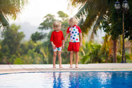 Child playing in swimming pool. Summer vacation with kids. Little boy jumping into water during exotic holiday in tropical island resort. Active outdoor sport for preschooler.の写真素材