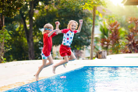 Child playing in swimming pool. Summer vacation with kids. Little boy jumping into water during exotic holiday in tropical island resort. Active outdoor sport for preschooler.の写真素材
