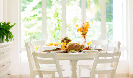 Thanksgiving dinner. Roasted turkey with stuffing and vegetables for family celebration. Autumn holiday table setting. Delicious homemade food and drink at party. Pumpkin and fall leaf decoration.の写真素材