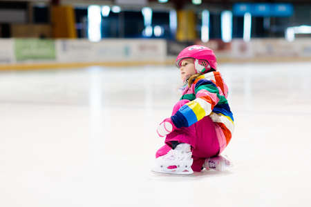 Child skating on indoor ice rink. Kids skate. Active family sport during winter vacation and cold season. Little girl in colorful wear training or learning ice skating. School sport activity and clubsの写真素材