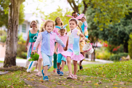 Easter egg hunt. Family with kids searching for colorful eggs. Children wear bunny ears. Boy and...