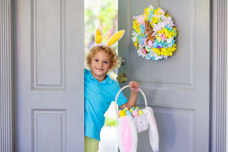 Kids at Easter egg hunt. Child holding basket with colorful chocolate eggs, wearing bunny ears....