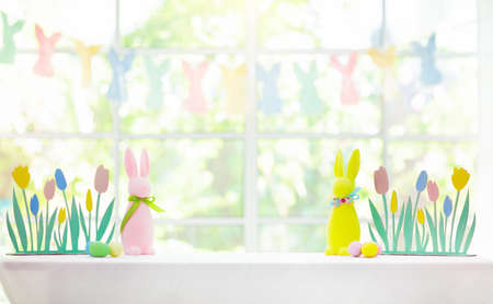 Easter home decoration. Basket with colorful dyed eggs and rabbit ears, tulip flowers and wooden...