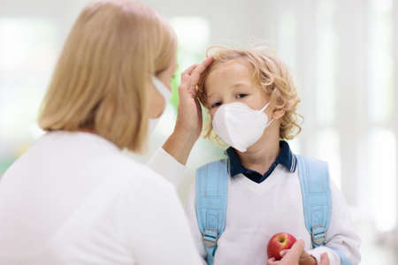 Family with kids in face mask going to school or kindergarten. Mother and child wear facemask during...
