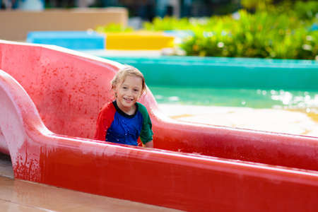 Kids on water slide in aqua park. Children having fun on water slides on family summer vacation in...