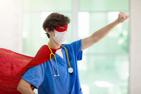 Doctor or nurse wearing surgical face mask in superhero cape. Medical staff during coronavirus outbreak. Super hero power for clinic and hospital personal.の写真素材