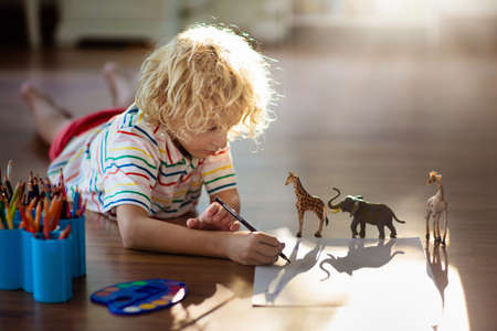Child shadow drawing animals. Kids play at home. Fun crafts for kindergarten children. Little boy painting giraffe and elephant in sunny bedroom. Games and art during coronavirus quarantine lockdown.の写真素材