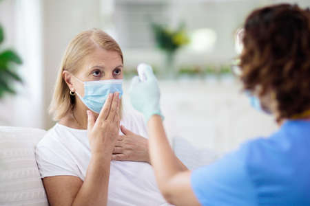 Doctor examining sick patient in face mask. Ill woman in health clinic for test and screening. Home treatment of virus. Coronavirus pandemic. Covid-19 outbreak. Woman coughing, having chest pain.の写真素材