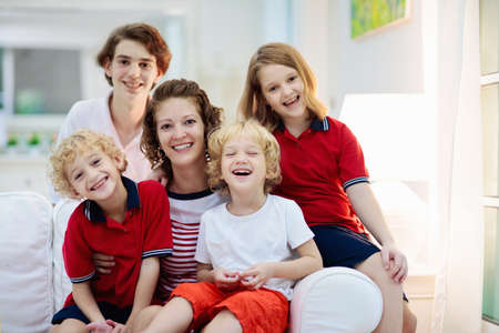 Mother and kids at home. Happy family with children. Mom and four school and preschool age children in uniform. Woman holding kid. Parents and child playing.の写真素材
