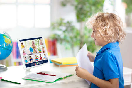 Online remote learning. School kids with computer having video conference chat with teacher and...