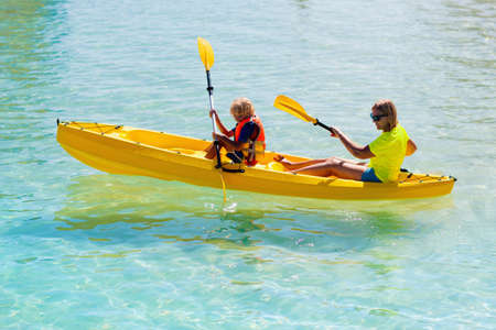 Kids kayaking in ocean. Children in kayak in tropical sea. Active vacation with young kid. Parents, little boy and girl in canoe on beautiful beach. Holiday activity with child. Family water fun.の写真素材