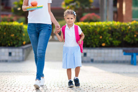 Mother and kids after school. Young mom picking up children after lessons in kindergarten or preschool. Pick up students. Boy and girl running to parents in school yard.の写真素材