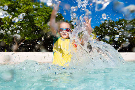 Kids playing on tropical beach. Children swim and play at sea on summer family vacation. Sand and water fun, sun protection for young child. Little boy running and jumping at ocean shore.の写真素材