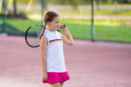 Child playing tennis on indoor court. Little girl with tennis racket and ball in sport club. Active exercise for kids. Summer activities for children. Training for young kid. Child learning to play.の写真素材