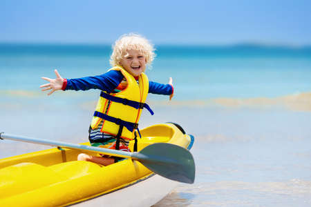 Kids kayaking in ocean. Children in kayak in tropical sea. Active vacation with young kid. Little boy in canoe on beautiful beach. Holiday activity with preschool child. Family water fun.の写真素材