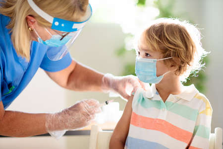 Coronavirus vaccination. Covid-19 vaccine. Doctor vaccinating child. Kids at clinic. Little boy getting flu shot. Pediatrician examining kid and giving injection. Virus prevention. Health care.の写真素材