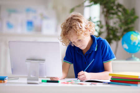 Online remote learning. School kids with computer having video conference chat with teacher and class group. Child studying from home. Homeschooling during quarantine and coronavirus outbreak.の写真素材