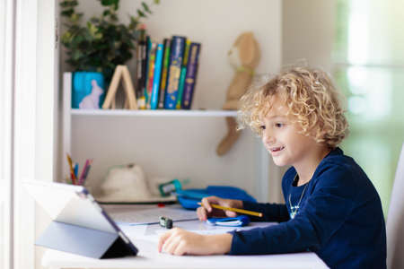 Online remote learning. School kids with computer having video conference chat with teacher and...