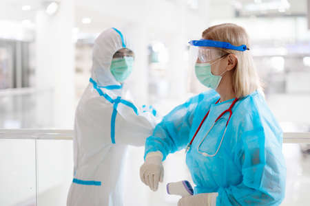International doctor team. Hospital medical staff in hazmat suit, face shield and mask. Mixed race...