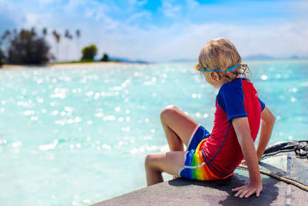 Kids jump into sea. Yacht vacation with child on exotic tropical island with crystal clear water. Beach and swim fun. Sailing and cruise with children. Summer holiday on boat. Little boy swimming.の写真素材