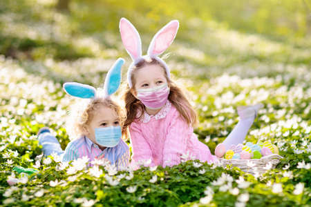Easter egg hunt in spring garden. Kids searching for colorful eggs and sweets hidden in blooming...